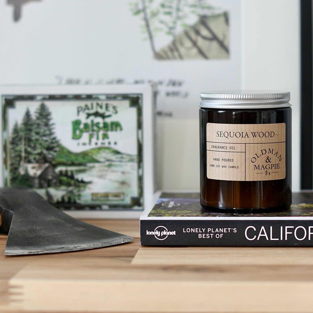 Old Man and Magpie's soy candle, in sequoia wood fragrance.  The candle is sat on top of a Lonely Planet guide to California book.