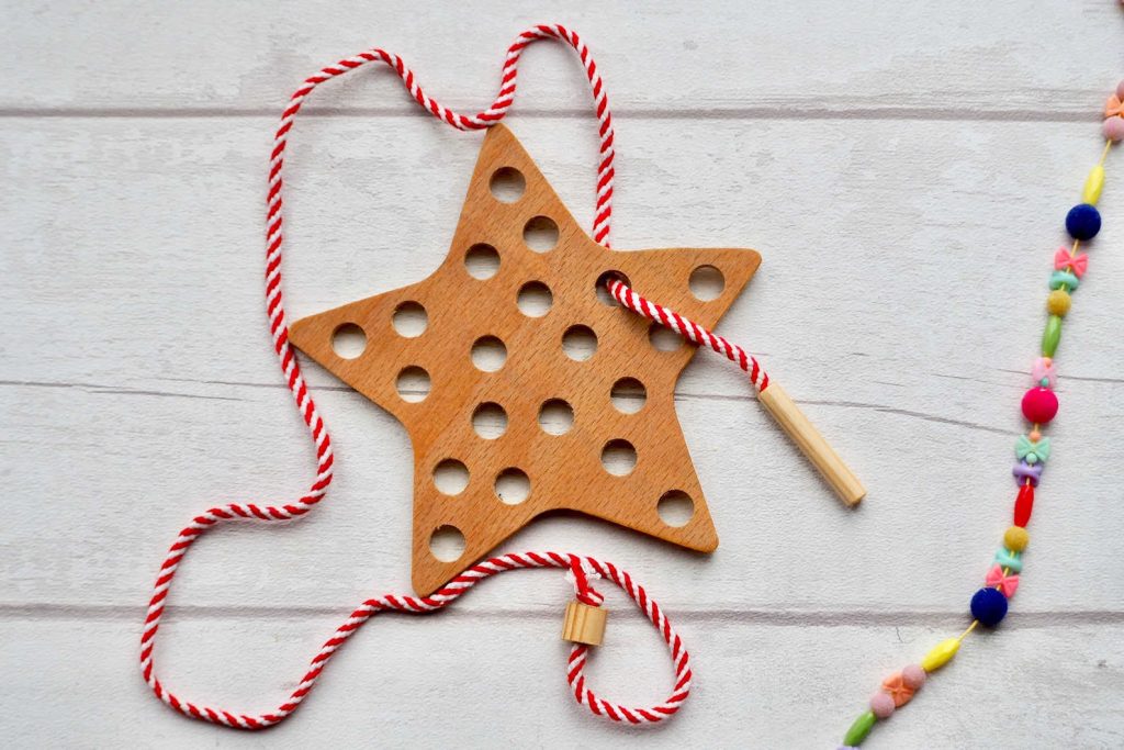 A wooden star, with holes for threading red and white striped cotton through - a great eco-friendly stocking filler.