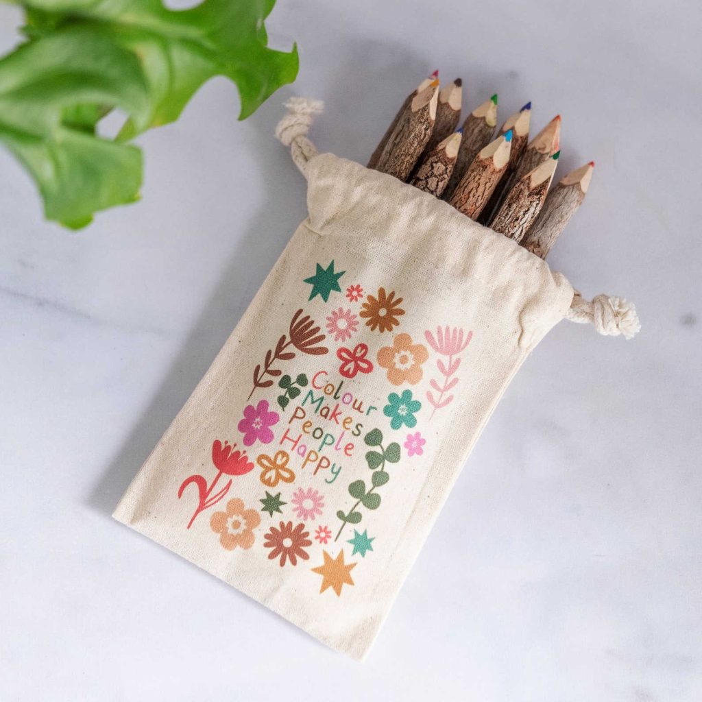 A set of wooden colouring pencils made from twigs, in a cotton bag printed with flowers that says colour makes people happy. Part of a series on eco-friendly stocking filler ideas.