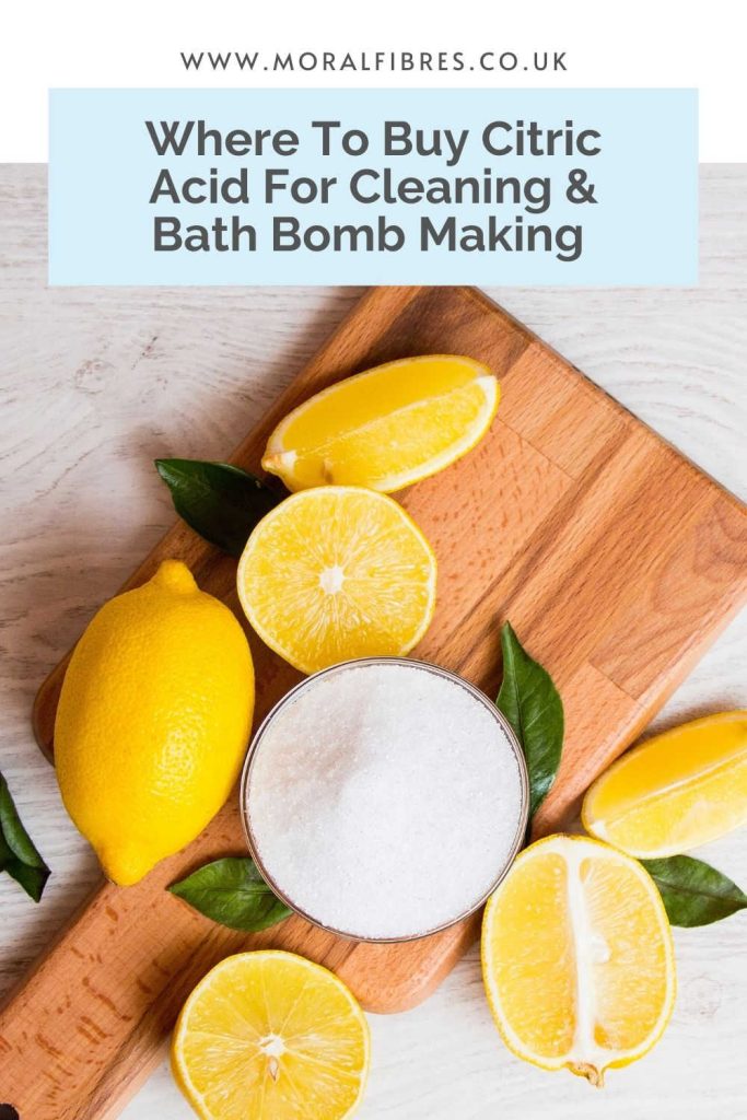 Image of chopped up lemons on a chopping board, next to a bowl of citric acid, with a blue text box that says where to buy citric acid for cleaning and for bath bomb making.