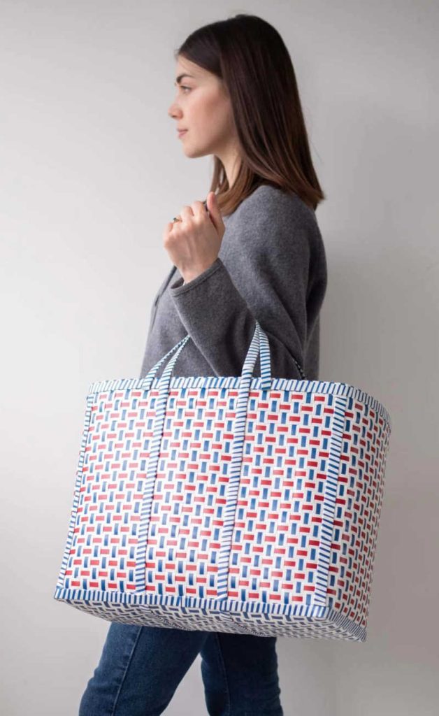 Person holding YGN Collective beach bag made from recycled pallet banding.