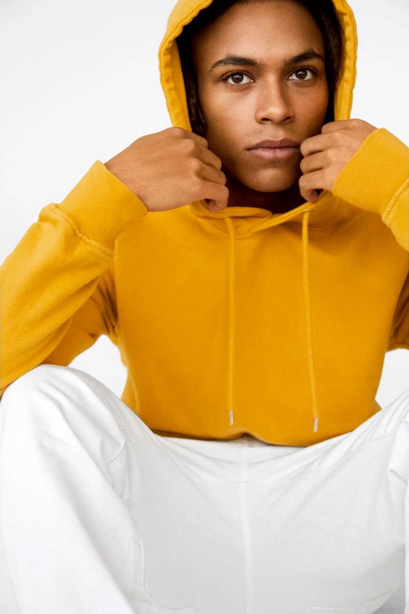 Person wearing yellow Colorful Standard hooded jumper