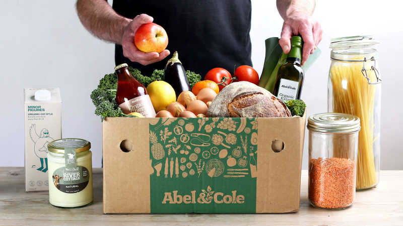Person unpackaging a packaging and plastic-free fruit and vegetable box from Abel & Cole.