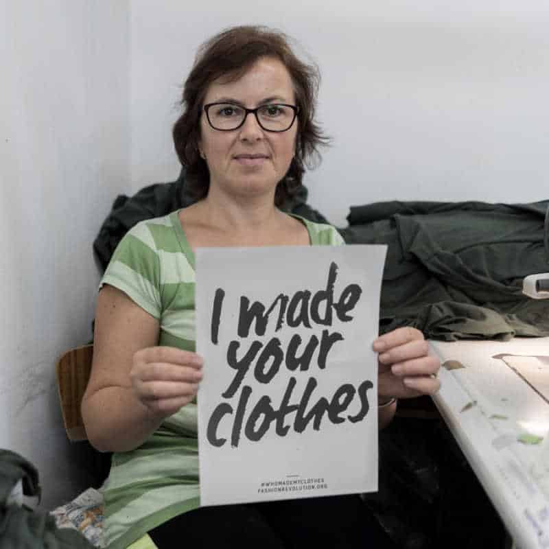 Garment professional holding sign saying I made your clothes, as part of the Fashion Revolution awareness week.