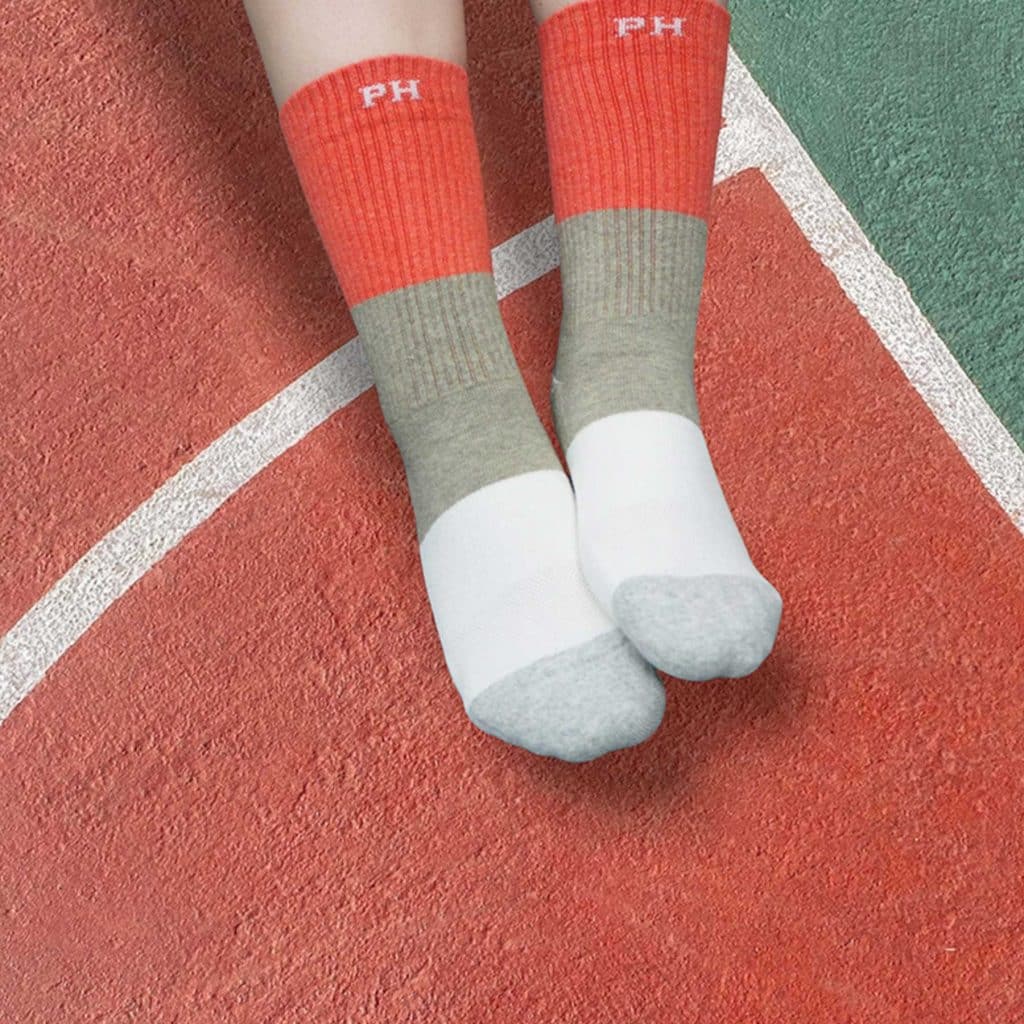 Person wearing Peper Harow recycled sports socks in coral.
