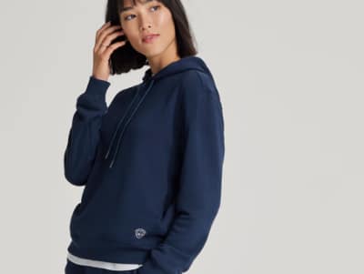 Person wearing a navy sustainable hoodie from Allbirds.