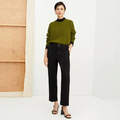 Person wearing black trousers and a green top from ethical clothing brand Kowtow.