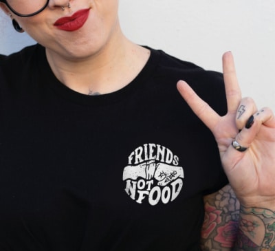 Person wearing a black vegan-friendly t-shirt that says friends not food.