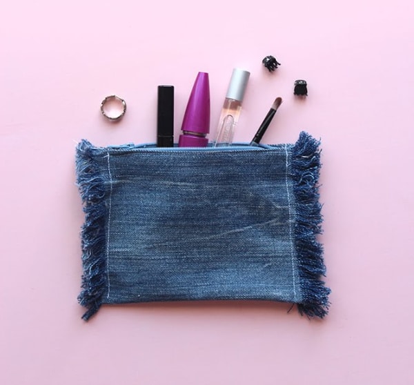 Upcycled denim makeup bag on pink background.