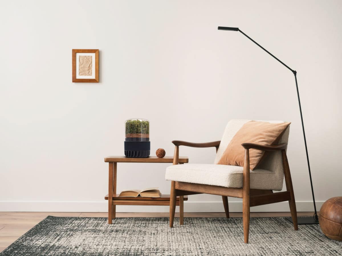 A stylish sustainable air filter on a coffee table next to a chair and lamp.