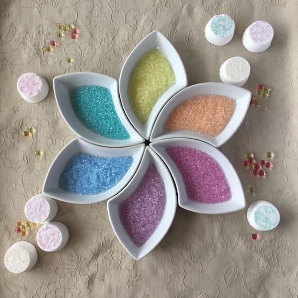 Various shapes of Epsom salt glitter in bowls the shape of a flower. 