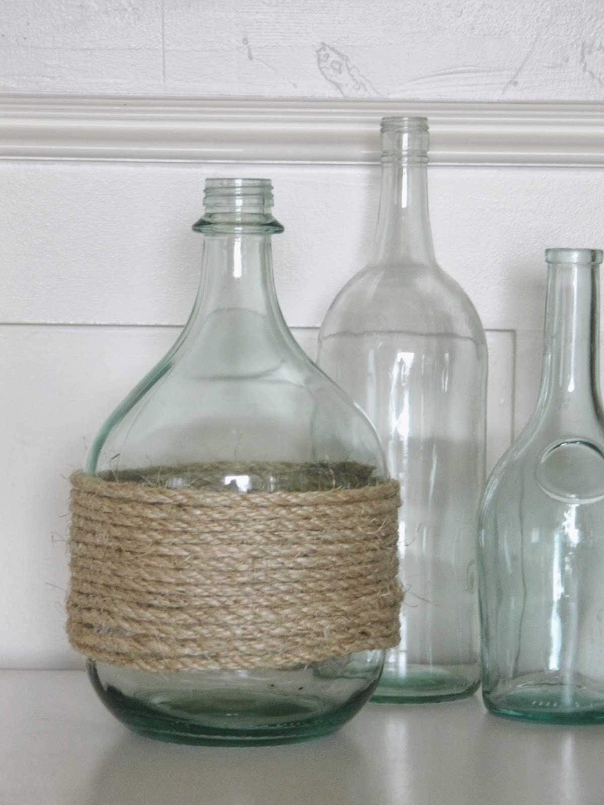 Glass bottle with rope around it, next to two other glass bottles