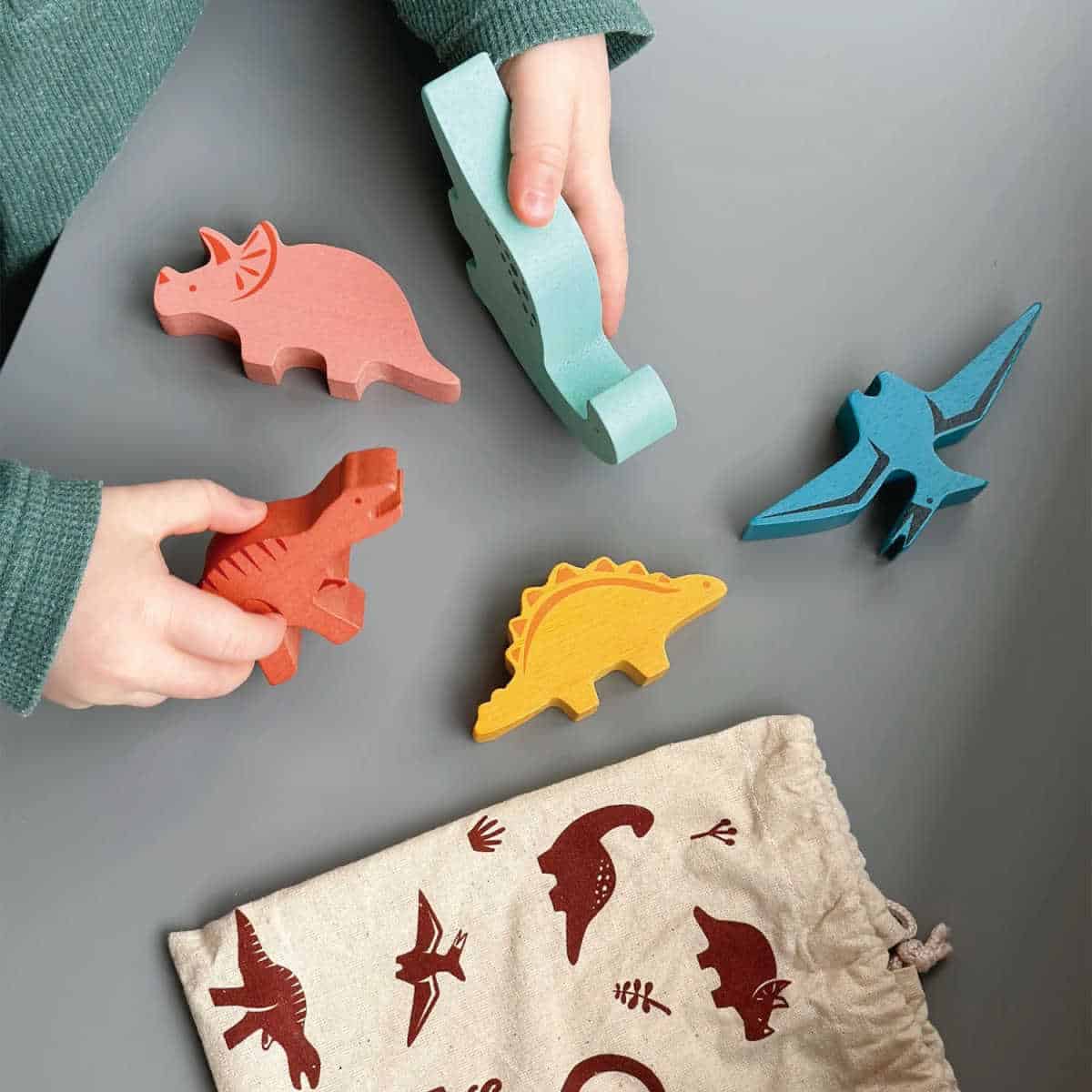 Child playing with sustainable wooden dinosaurs game