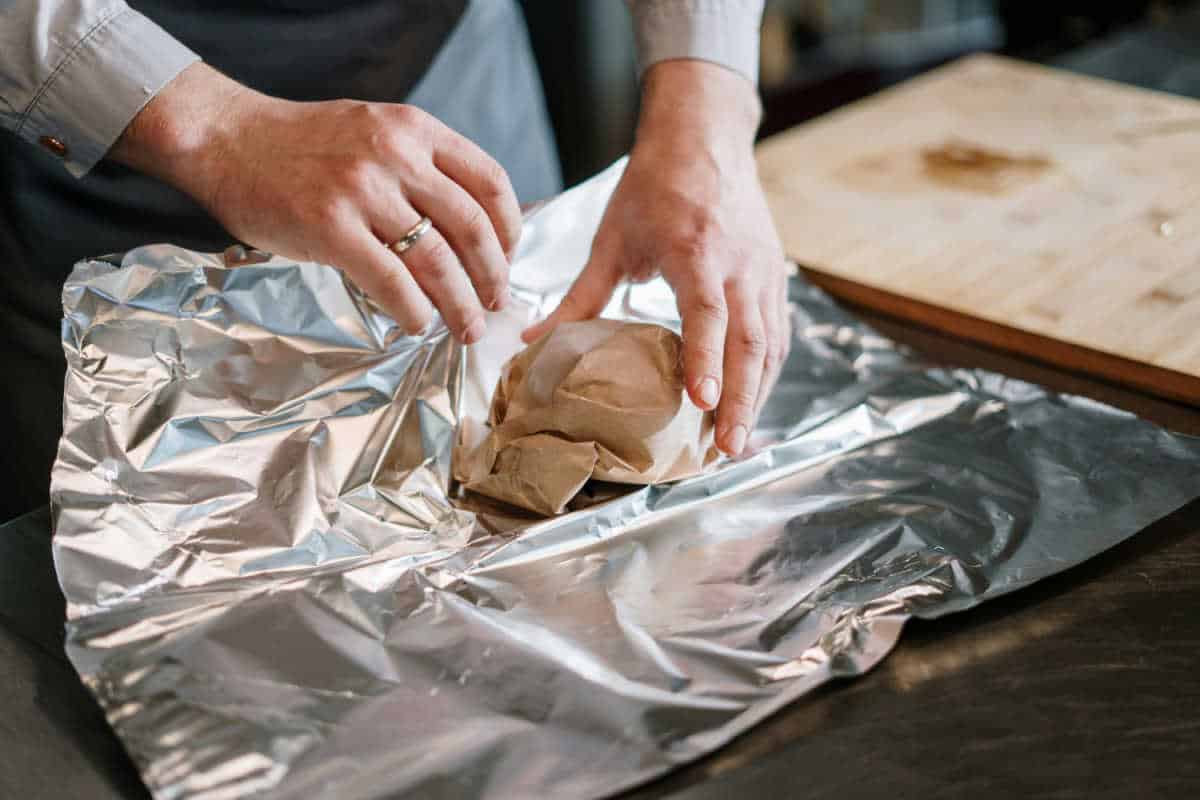 Person wrapping bread in tin foil