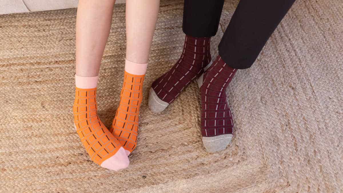 Person wearing orange socks next to someone wearing burgundy socks.