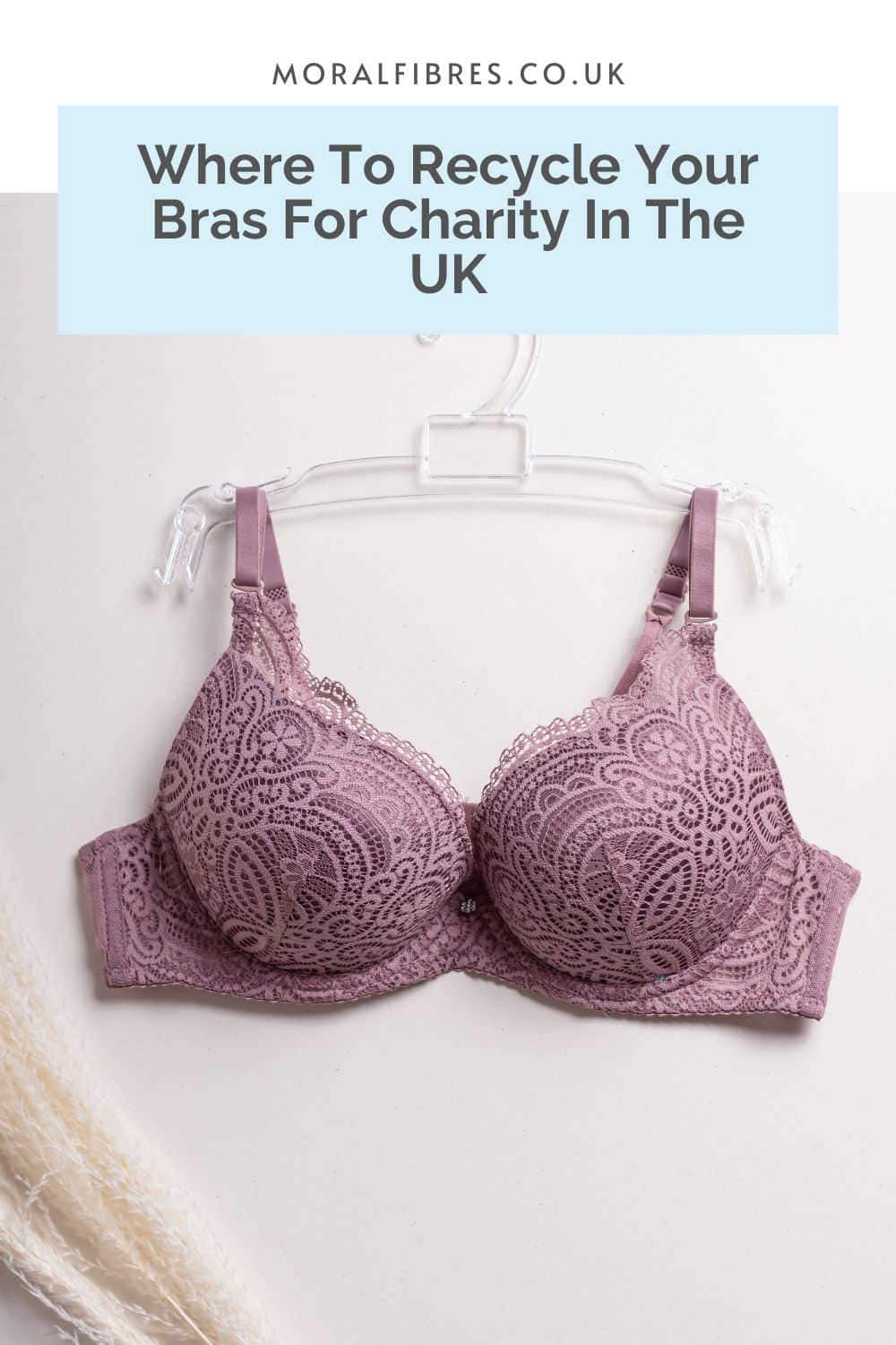 Purple bra hanging on a hanger against a white wall with a blue text box that reads where to recycle your bras for charity in the UK.