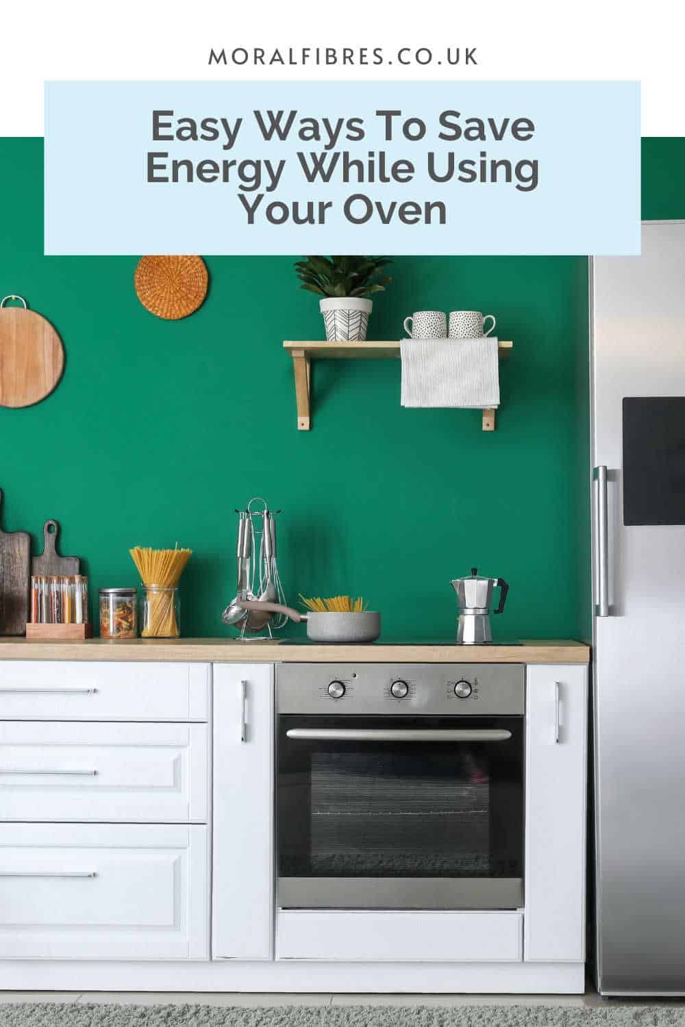 White kitchen units and stainless steel appliances in a dark green painted room, with a blue text box that reads easy ways to save energy while using your oven.