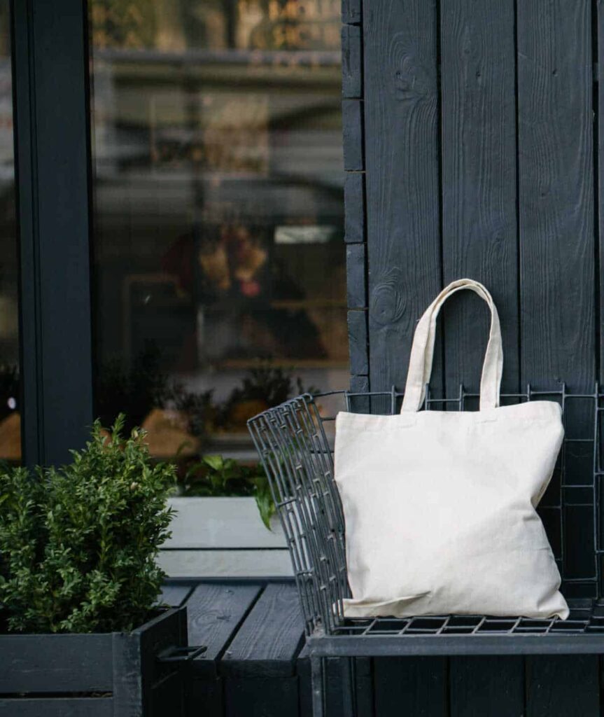 White cotton tote bag on a bench outside a dark wood building